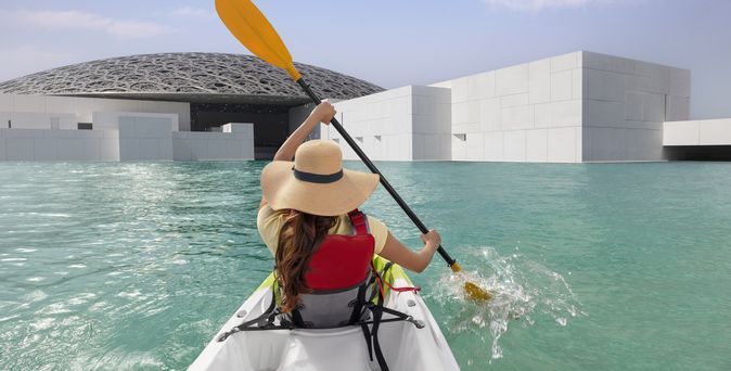 Eine Frau fährt in einem Kayak am Louvre in Abu Dhabi
