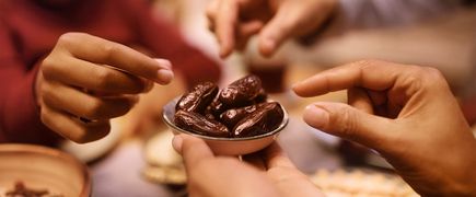 Mehrere Hände greifen in ein mit Datteln gefülltes Schälchen