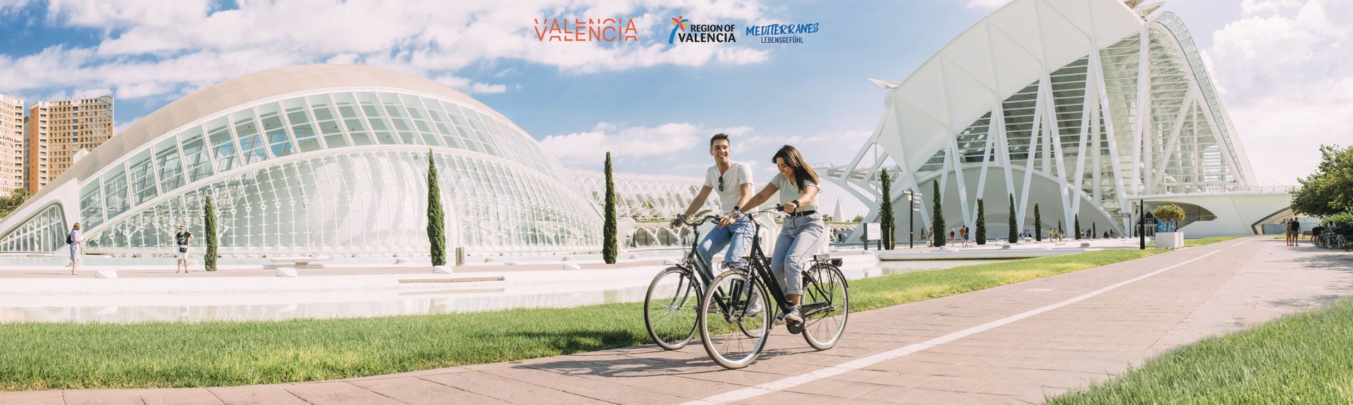 Eine Frau und ein Mann bei einer Fahrradtour entlang der Stadt der Künste und Wissenschaften in Valencia, Spanien
