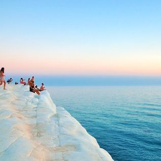 Menschen sitzen auf den Felsen von Scala dei Turchi auf Sizilien, Italien, und blicken aufs Mittelmeer