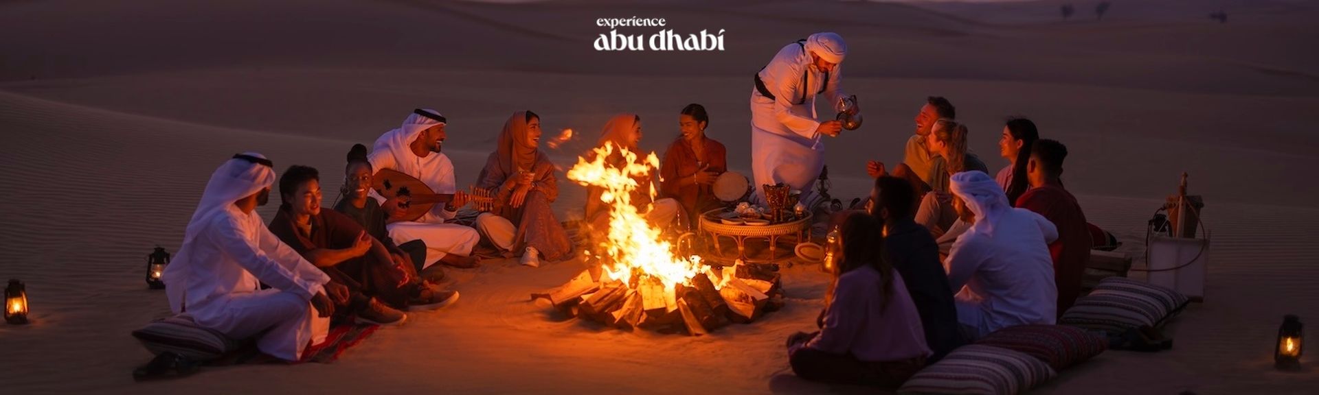 Eine Gruppe von Guides und Gästen sitzen um ein Lagerfeuer in der Wüste Abu Dhabis