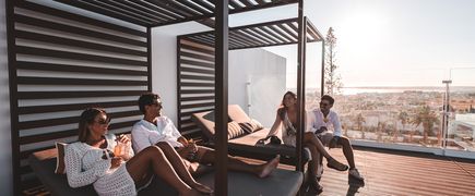 Eine Gruppe von Freunden auf Sitzgelegenheiten einer stylischen Hotel-Dachterrasse