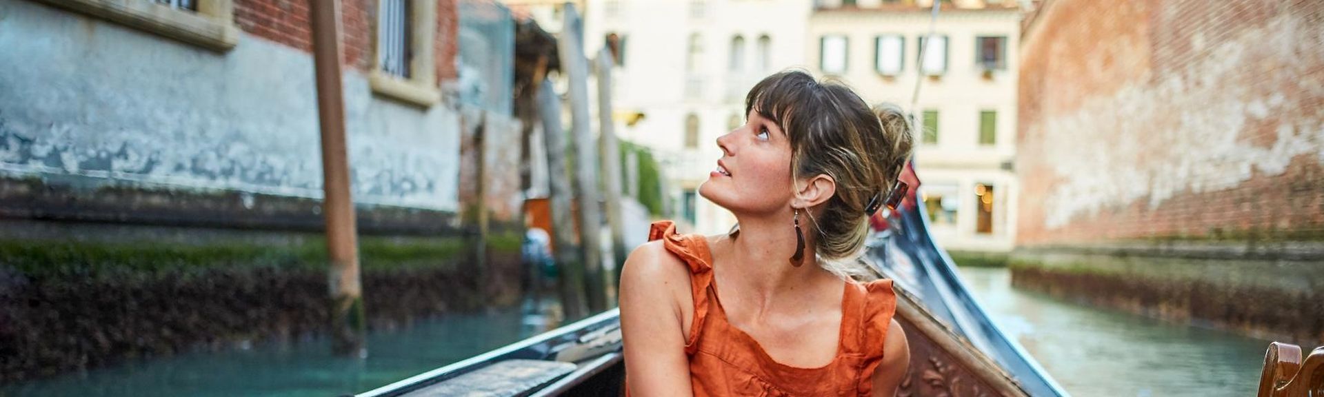 Eine Frau in einer venezianischen Gondel bewundert die Architektur Venedigs während der Fahrt