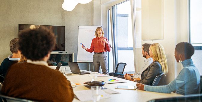 Konferenzteilnehmende hören in einem Besprechungsraum einer Vortragenden zu