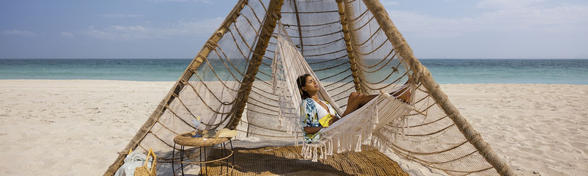Eine Frau entspannt in einer Hängematte am Strand von Abu Dhabi.