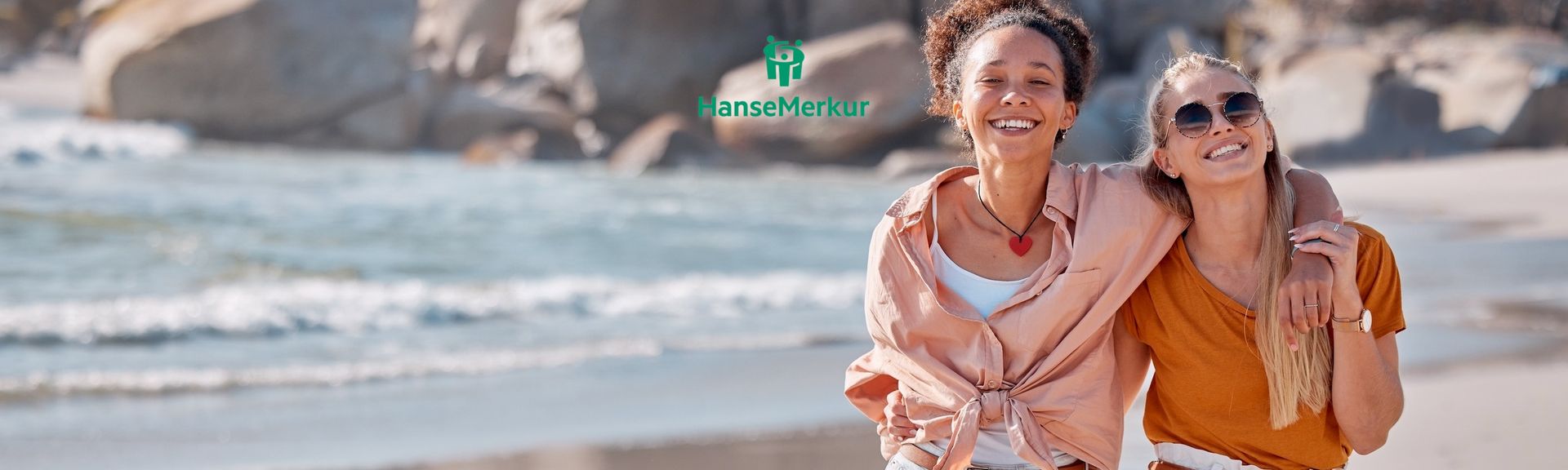 Zweit Freundinnen Arm in Arm an einem sonnigen Strand