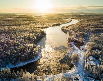 Eine verschneite Wald- und Flusslandschaft in Lappland von oben