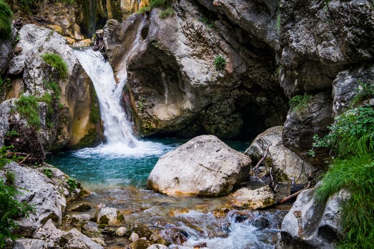 Kleiner Wasserfall in türkisfarbenes Wasser mit Steinen umgeben