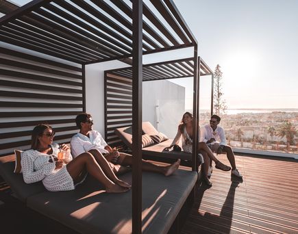 Eine Gruppe von Freunden auf Sitzgelegenheiten einer stylischen Hotel-Dachterrasse
