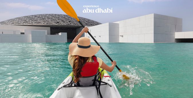 Eine Frau fährt in einem Kayak am Louvre in Abu Dhabi