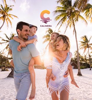 Familie mit zwei Kindern laeuft fröhlich an einem Strand entlang