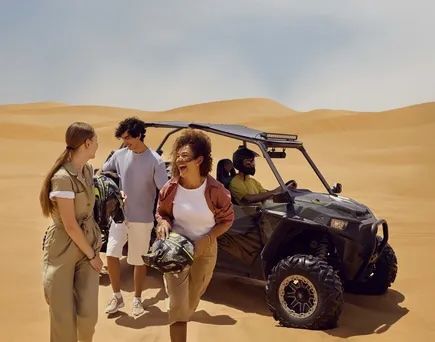 Eine Gruppe fröhlicher Gäste bei einer Wüstentour vor den Toren Abu Dhabis.