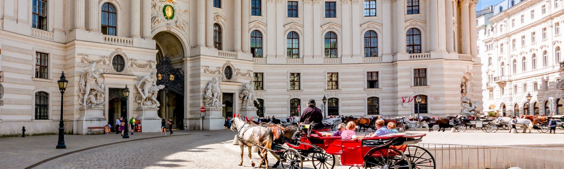 Blick auf die Wiener Hofburg bei sommerlichem Wetter und regem Treiben