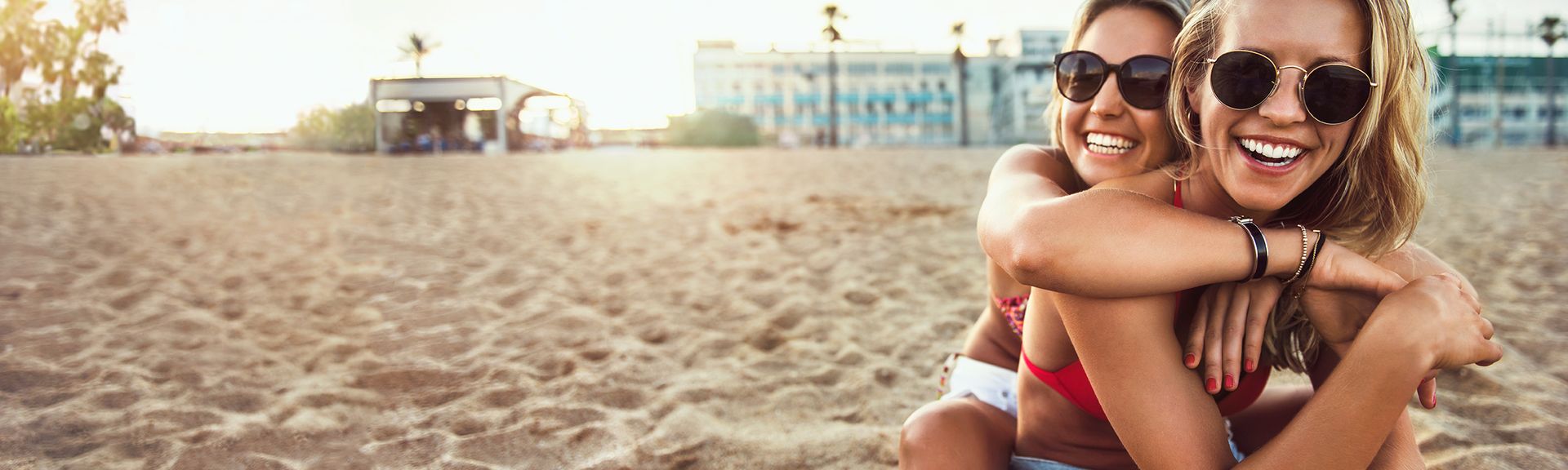 Zwei Frauen sitzend und umarmend am Strand 
