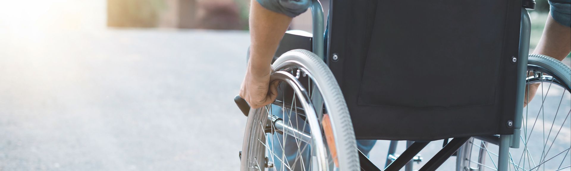 Close-up eines Rollstuhls, in dem ein Mann sitzt